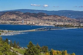 A view of the bridge over Okanagan Lake between West Kelowna and Kelowna Brititsh Columbia Canada with a view of the Kelowna skyline and a marina in the foreground.