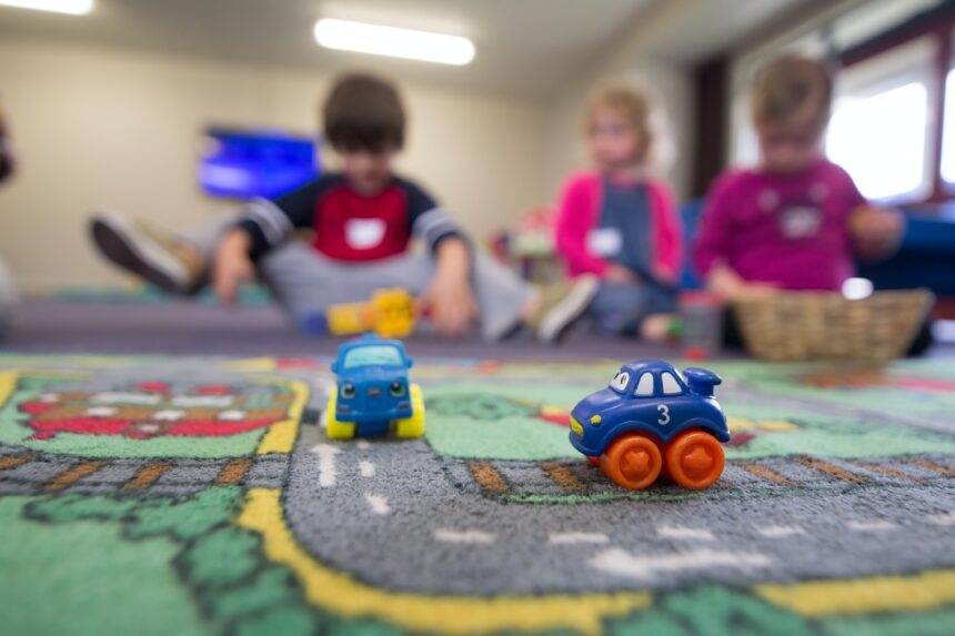 A close-up of plastic miniature toys and a group of children playing with them. A child deserves a safe and secure life. Therefore, PM Trudeau announced $10-a-day child care in Canada.