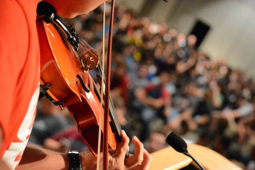 A close-up of a person playing violin and performing in front of the audience. There will be an event of Candlelight's Homage to Adele.
