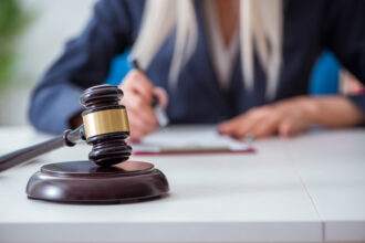 A picture of a lady sitting in the background and the judge's gavel kept on the table.