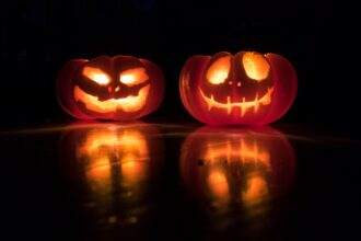 Two spooky carved pumpkins in the dark give a Halloween Resurrection vibe.