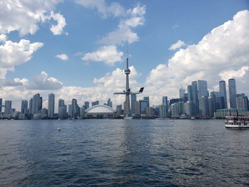 A view of the entertainment district of Toronto with high-rise buildings in the background and a waterbody in the front.