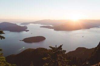 A skyline view of British Columbia in Vancouver. A clear sky during the sunset time and a waterbody beneath the sky.