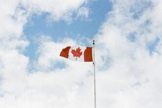 A Canadian flag is high up in the sky.