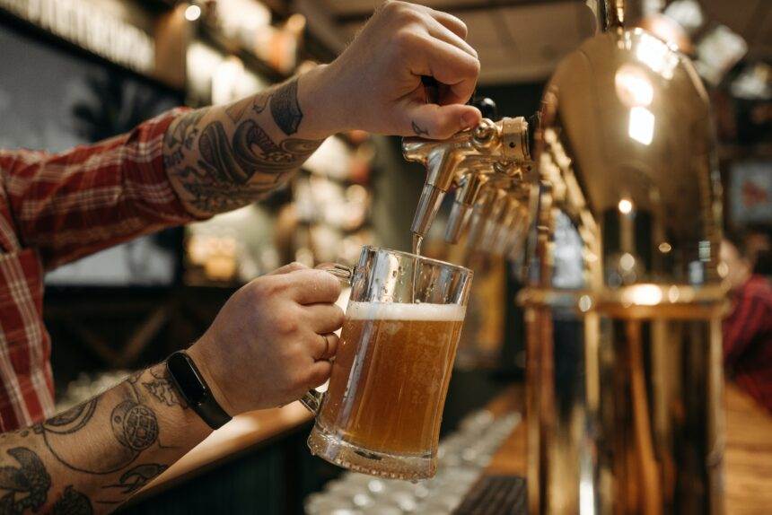 A person pouring out beer in a beer glass.