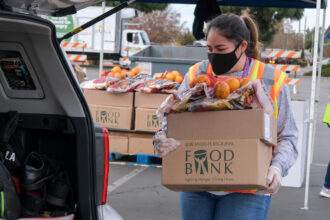 A volunteer holding a big carton of food for one of the food banks in Vancouver.