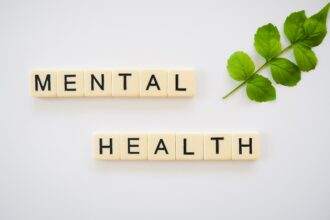 Mental health is spelled out with wooden scrabbles on a white background.