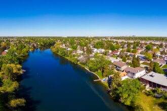 A drone view of a river and green land of grasses and trees in Winnipeg.
