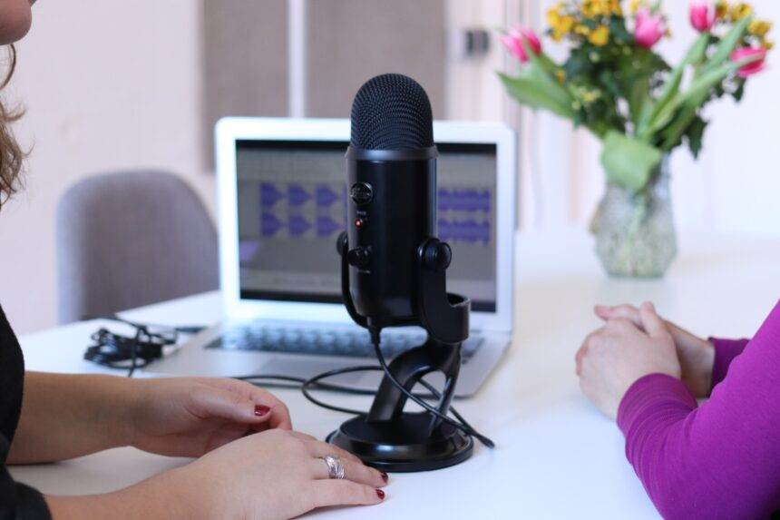 A close-up of a mic and two women talking over it.