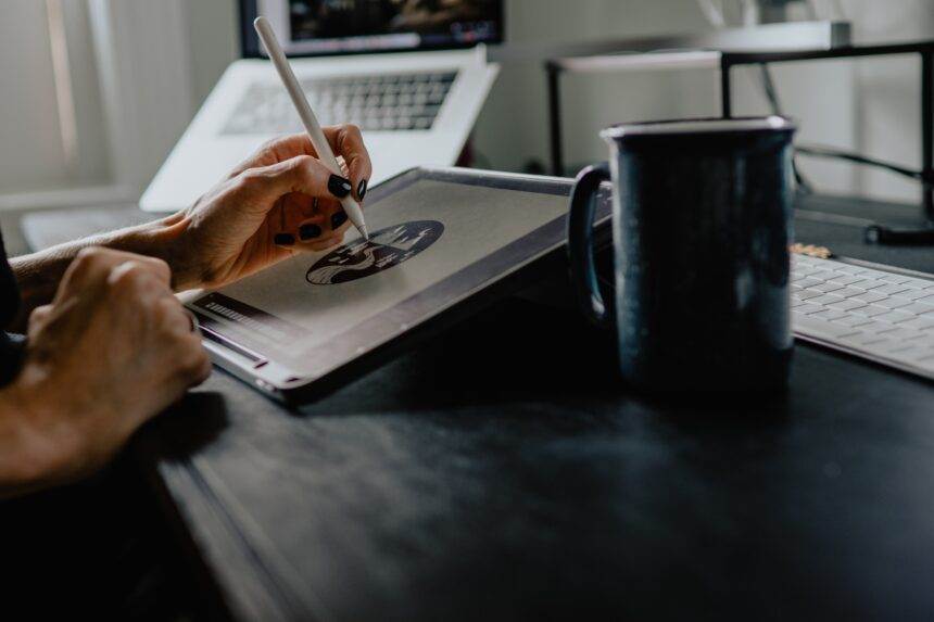 Person holding silver pen on a tablet.