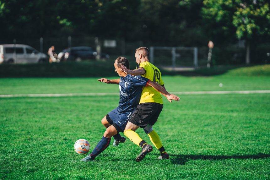 Two person kick the soccer ball