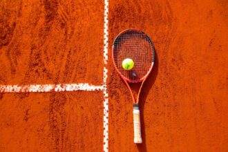A top view of a tennis racket and a ball kept on the tennis ground.
