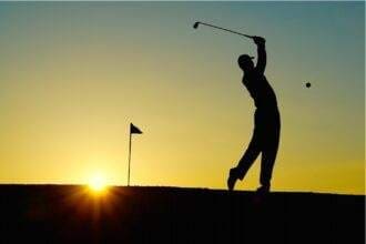 A silhouette of a person hitting the golf ball in the golf club