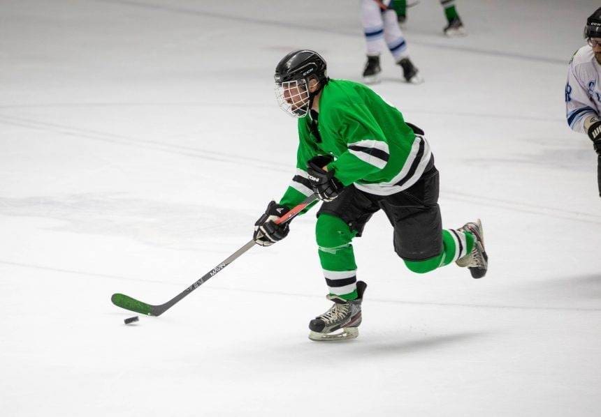 A player with a green jersey playing a hockey game.