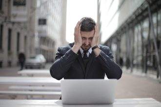 A stressed employee sitting in front of his laptop.