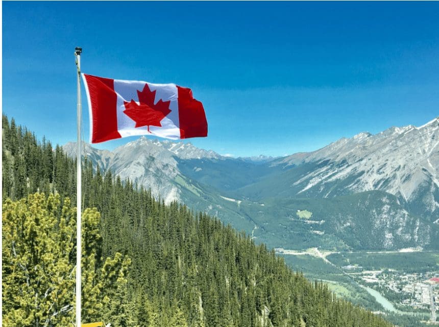 Canadian flag waving with mountainous backdrop