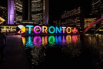 Toronto cityscape at night with illuminated sign and reflections.