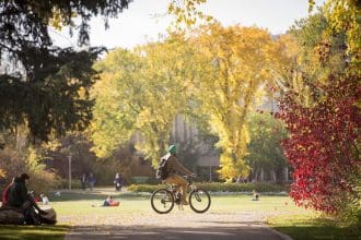 Autumn scenery with cyclist and students on a university campus in Saskatchewan.