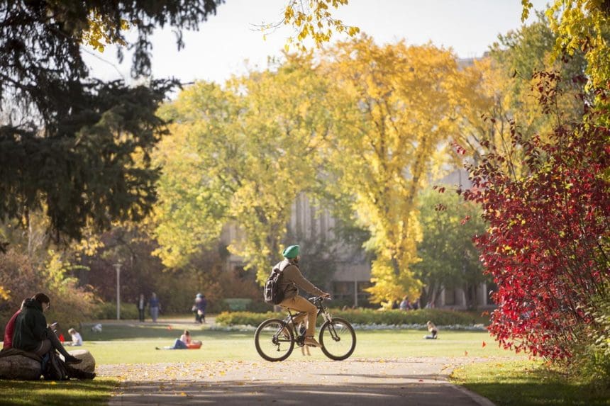 Autumn scenery with cyclist and students on a university campus in Saskatchewan.