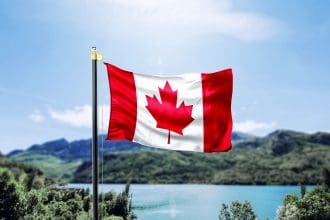 Canadian flag waving before mountainous lake landscape
