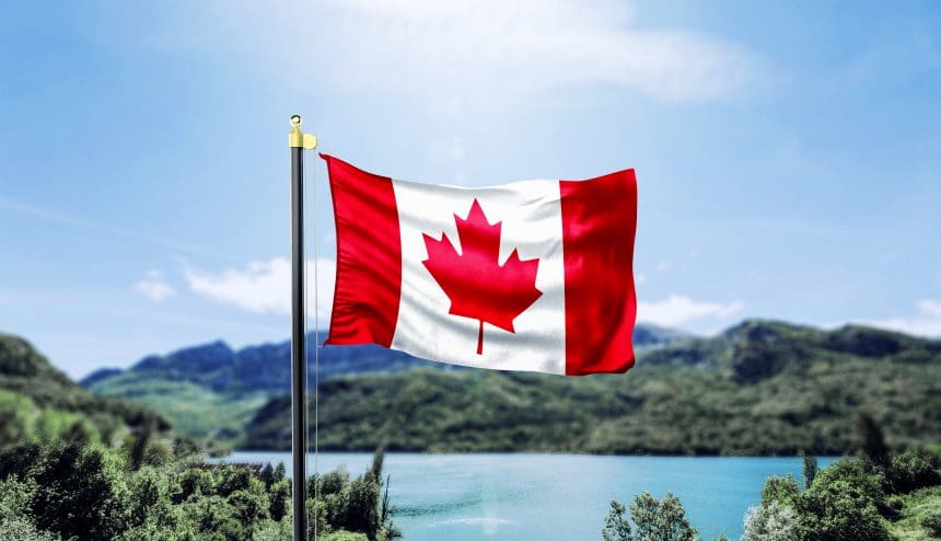 Canadian flag waving before mountainous lake landscape
