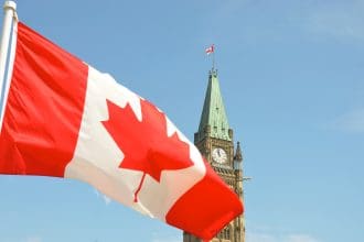 Canadian flag waving in front of Parliament Hill.