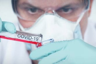 Scientist examining COVID-19 sample in lab.