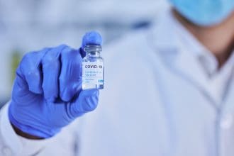 Scientist holding COVID-19 vaccine vial in laboratory.