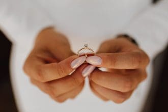 Bride with manicured hands presenting engagement ring.