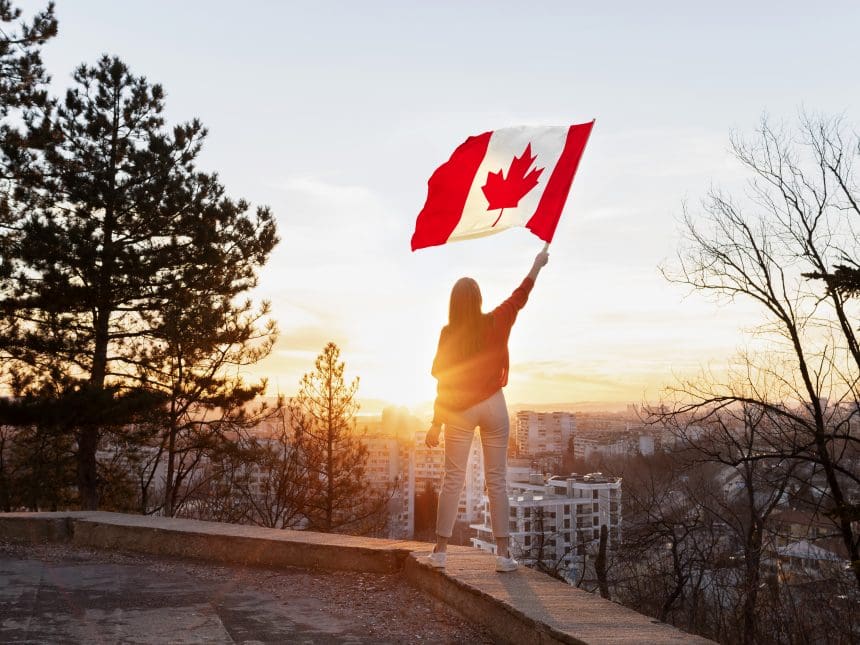 Woman holding Canadian flag at sunset