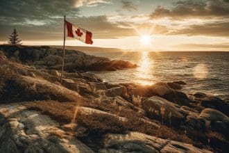 Canadian flag over coastal rocks at sunset